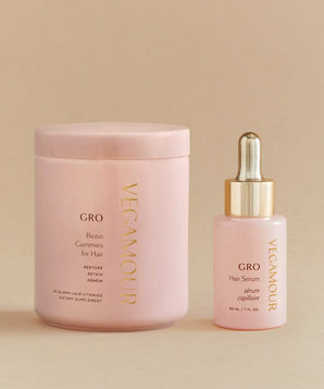 A GRO More Kit by VEGAMOUR, a pink hair serum bottle with a gold lid next to it, designed to increase hair density.